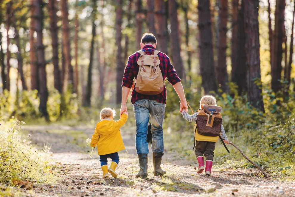 En man och två barn som promenerar i skogen.