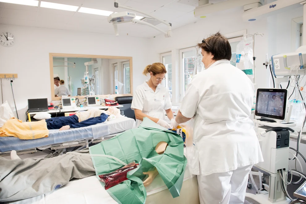 Två kvinnor i ett sjukhusrum med medicinsk utrustning.